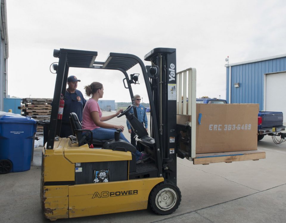 District staff driving a fork lift at district headquarters