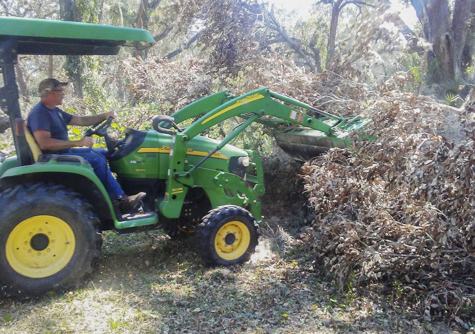 District staff using a frontloader to move tree debris