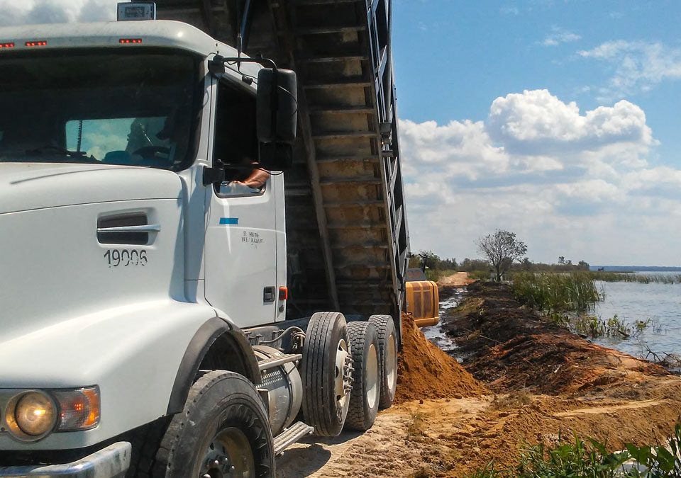 Dump truck delilvering fill material to a levee on Lake Apopka's north shore