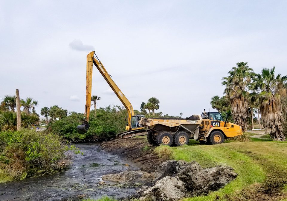 Backhoe expanding a stomwwater containment area on a golf course