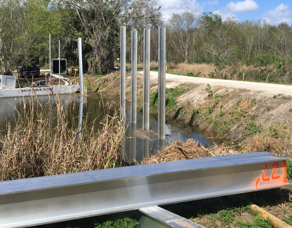 Levee cutting across a wetland with metal beams jutting out of the water