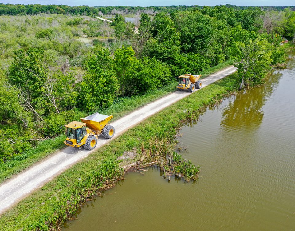 Dump trucks driving on a levee along Lake Apopka