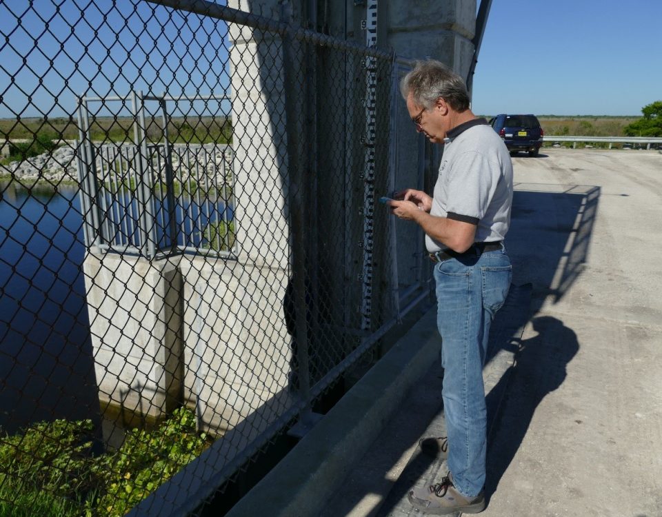 John Richmond using his cell phone to test a water control structure