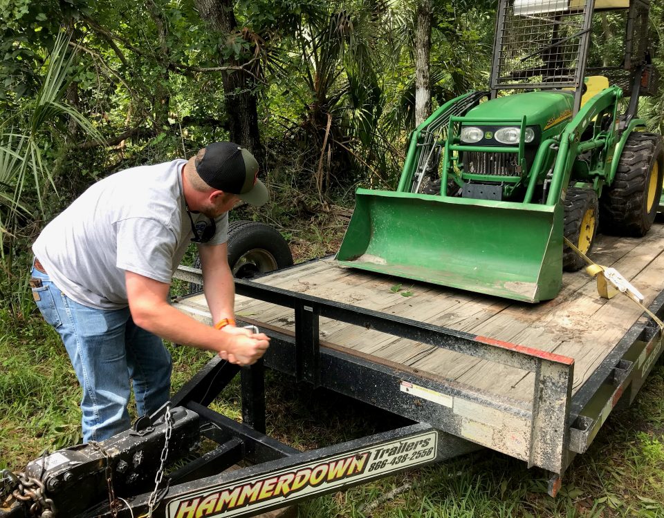 District staff member unloads a tractor from a trailer