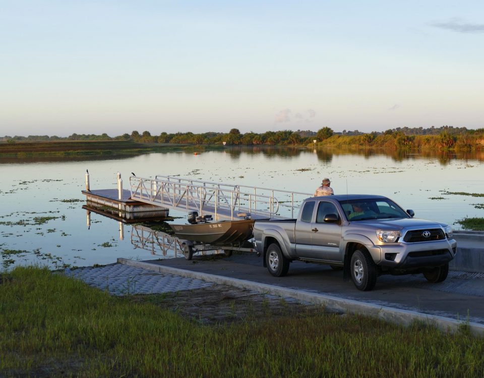 Man using a Toyota truck to load a small pontoon boat