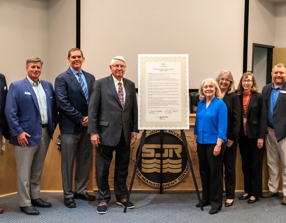 Disctict board members posing next to a plaque