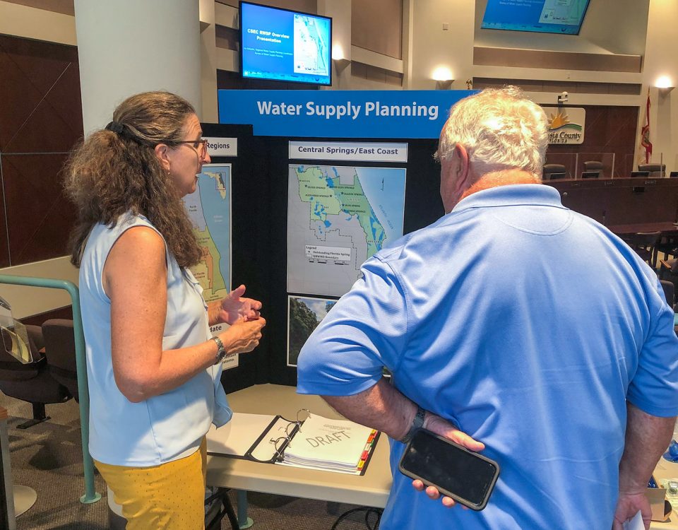 Two people talking in front of a display about water supply planning